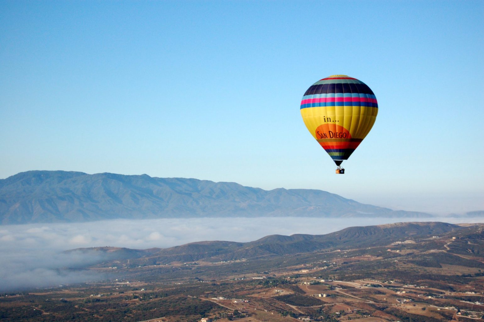 a large balloon in the air with a mountain in the background